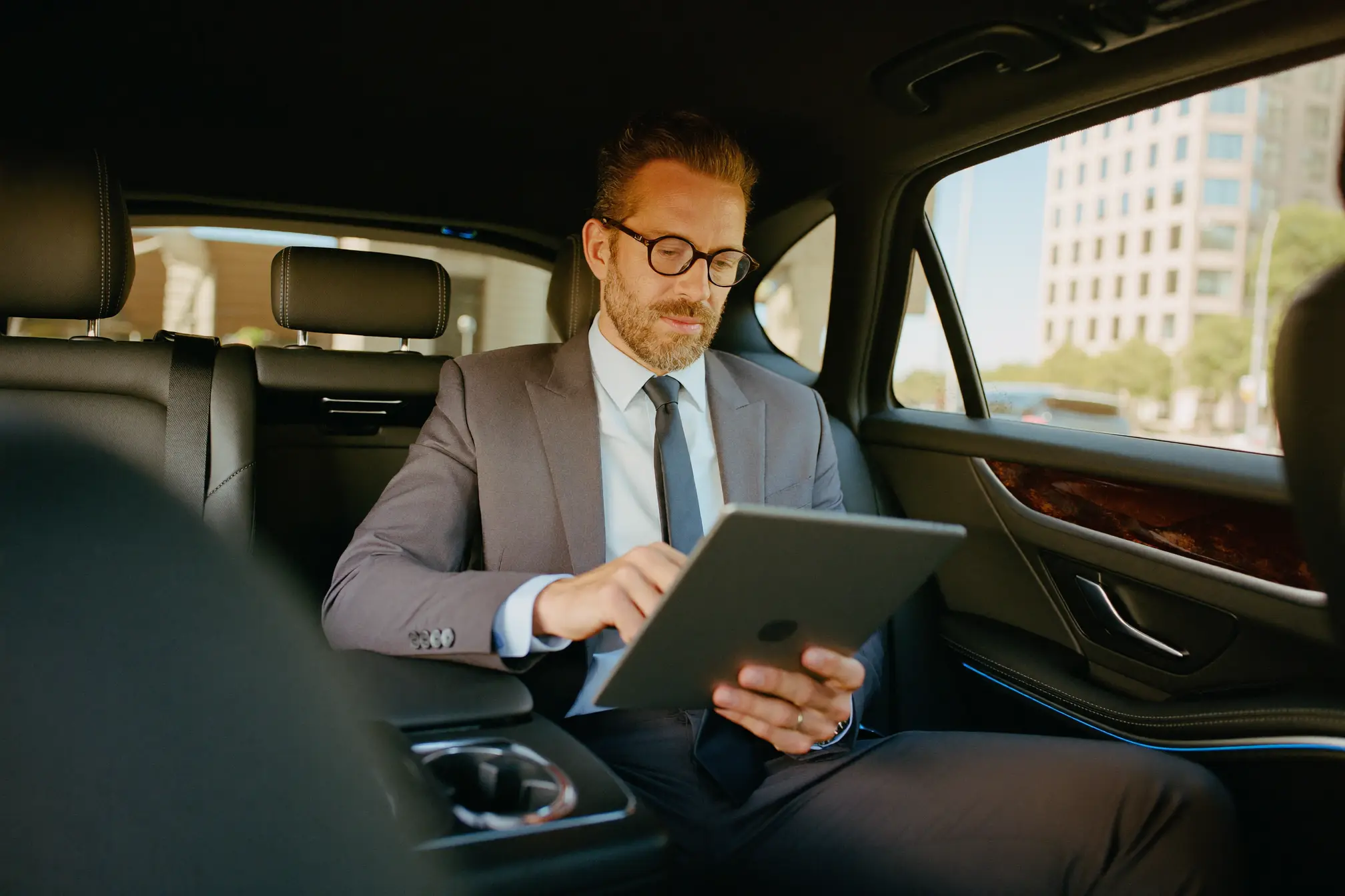 A passenger working on a tablet in the back seat.