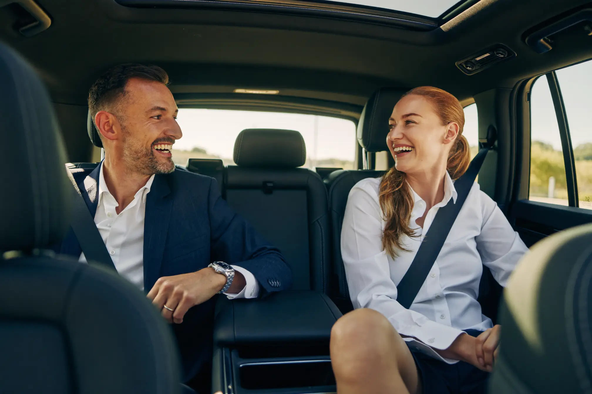 Two colleagues talking in the back seat of the vehicle.
